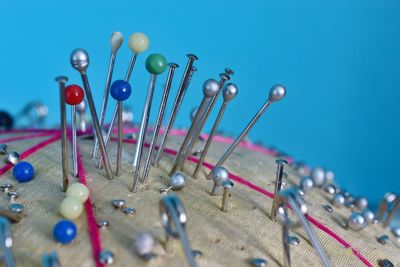 Close-up of straight pins on cushion against blue background