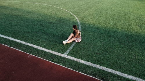 Young woman sitting on sport field