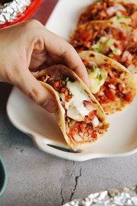 Close-up of hand holding pizza on table