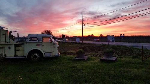 Cars on field against sky during sunset