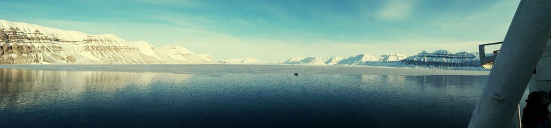 Scenic view of lake by snowcapped mountains against sky