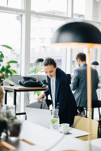 Businesswoman examining file while standing at desk office cafeteria