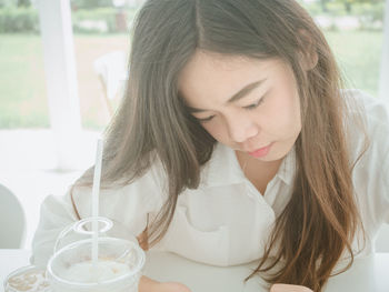 Close-up of young woman looking down by disposable cup