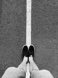 Low section of man standing on road marking