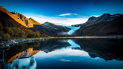 Scenic view of lake and mountains against blue sky