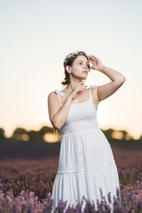 Portrait of smiling young woman standing against sky during sunset