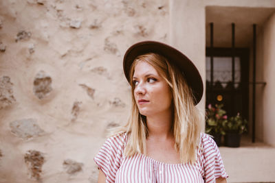 Blonde woman with her head turned sideways visiting an ancient city