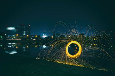 Man spinning wire wool while standing against river in city