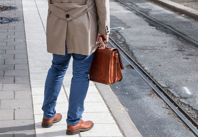 Low section of man standing on street in city