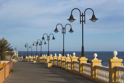 Street lights by sea against sky