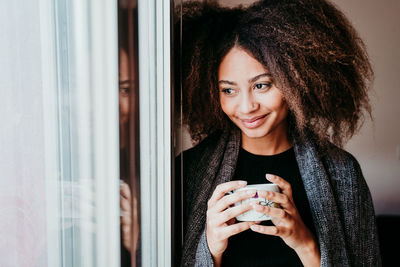 Portrait of a smiling young woman holding smart phone