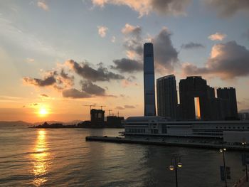 Scenic view of sea by buildings against sky during sunset