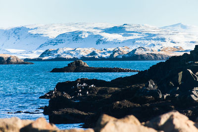 Scenic view of sea and snowcapped mountains against sky