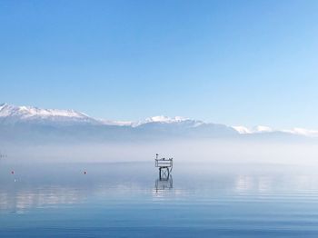Scenic view of sea and mountains against blue sky