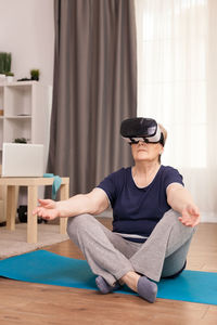 Senior woman exercising wearing virtual reality simulator at home
