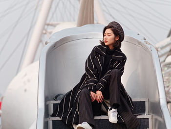 Young woman looking away while sitting outdoors