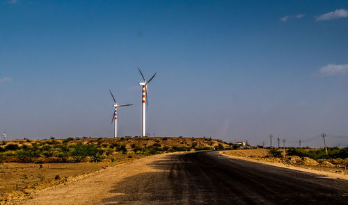 Windmill on road against sky