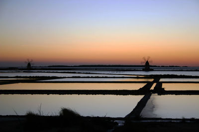 Silhouette man by sea against sky during sunset