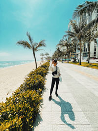 Full length of man on palm tree on beach