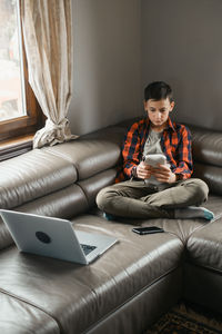 Young woman using laptop while sitting on sofa at home