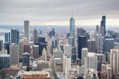 Aerial view of buildings in city against cloudy sky