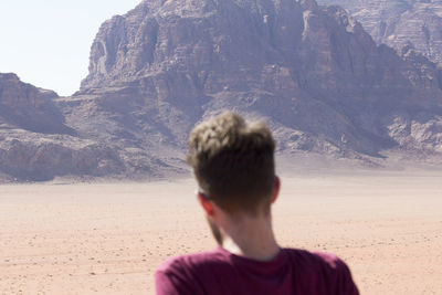 Rear view of man on rock against sky