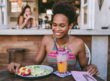 Close-up of young woman having food and drink on table