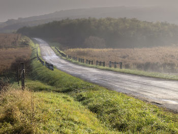 Road amidst field against sky