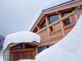 Low angle view of snow covered house against sky