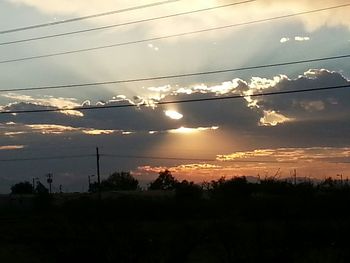 Electricity pylon against cloudy sky