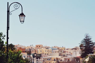 Street light and houses against clear blue sky