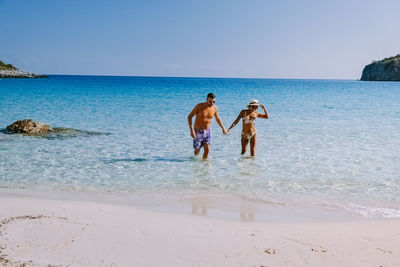 Friends enjoying on beach against sky