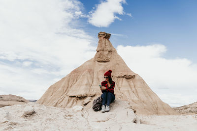 Low angle view of person on rock against sky