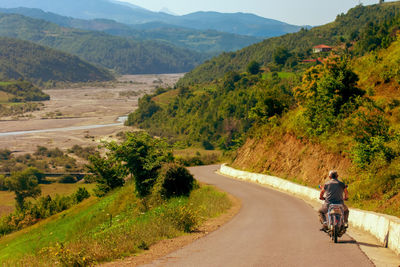 Rear view of man riding motorcycle on road