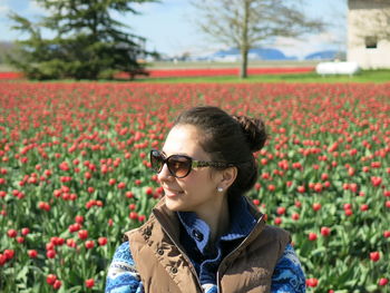 Young woman with sunglasses standing amidst flowers