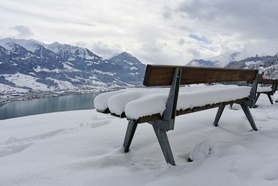 Snow covered field by snowcapped mountain against sky