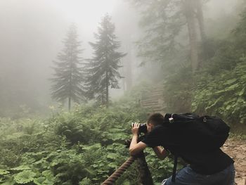 Man photographing through camera in forest