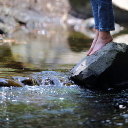 Low section of child standing on rock by river