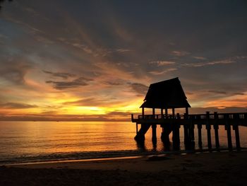 Silhouette pier on beach against sky during sunset