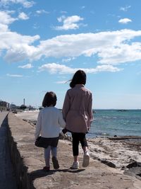 Rear view of women on beach against sky