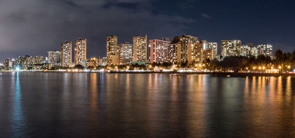 Sea against illuminated buildings in city at night