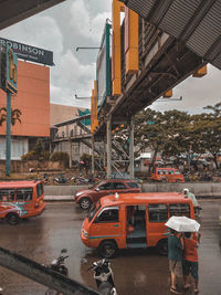 Cars on road by buildings against sky