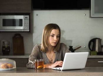 Woman working with laptop in kitchen