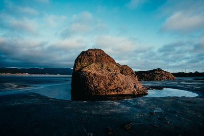 Rock formation on beach against sky