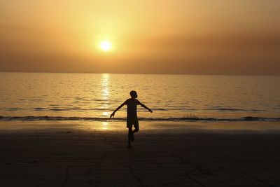 Silhouette man on beach against sky during sunset