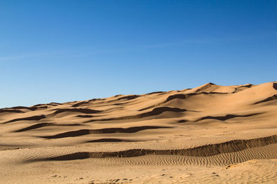 Scenic view of desert against clear blue sky