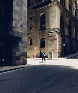 Man walking on road along buildings