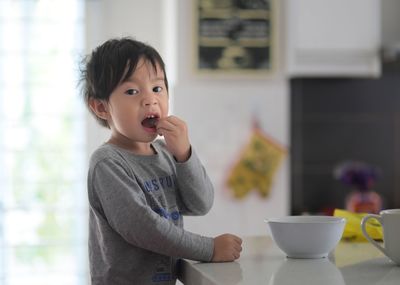 Portrait of boy eating food in kitchen
