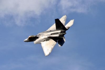 Low angle view of fighter plane flying in blue sky