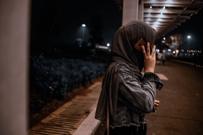 Side view of teenager talking on smart phone at night